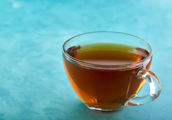 Glas kopp te och choklad cookies närbild på blå bakgrund. — Stockfoto