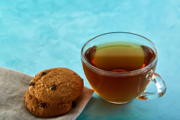 Glass cup of tea and oatmeal chocolate cookies close-up on blue background. — Stock Photo, Image