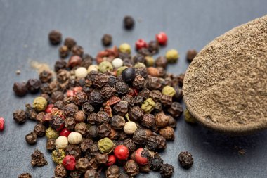 Eziyet kara biber ve karabiber dolu bir tahta kaşıkla üstten görünüm gri arka planda, sığ derinlik-in tarla.