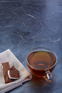 Bir cam bardak siyah çay ile çikolata koyu grimsi mermer arka plan, seçici odak, dikey.