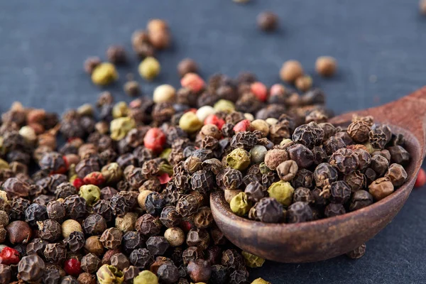 Tahta kaşık koyu arka planı, yakın çekim, sığ derinlik-in tarla peppercorns bileşimi — Stok fotoğraf