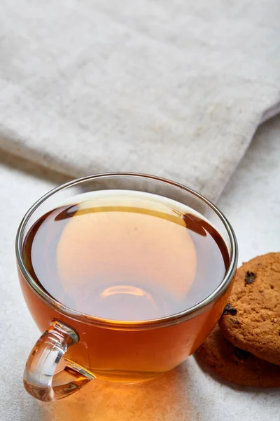 Top view closeup vertical picture of tea in transparent cup with cookies and napkin on white background, selective focus — Stock Photo, Image