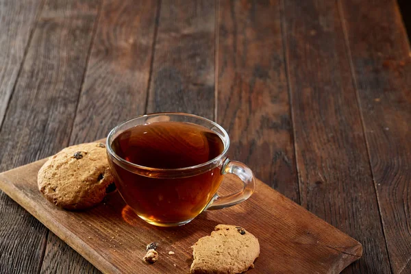 Taza de té con galletas en una tabla de cortar sobre un fondo de madera, vista superior, enfoque selectivo — Foto de Stock