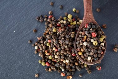 En koyu arka plan üzerinde tahta kaşık karabiber bileşimi görünüm yakın çekim.