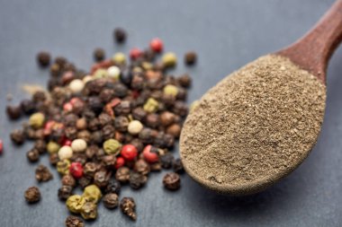 En koyu arka plan üzerinde tahta kaşık karabiber bileşimi görünüm yakın çekim.