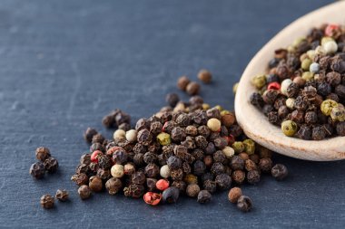 En koyu arka plan üzerinde tahta kaşık karabiber bileşimi görünüm yakın çekim.