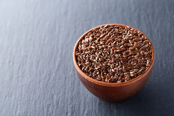 Koyu arka plan üzerinde izole bir kil kase keten tohumu yakın çekim resim.