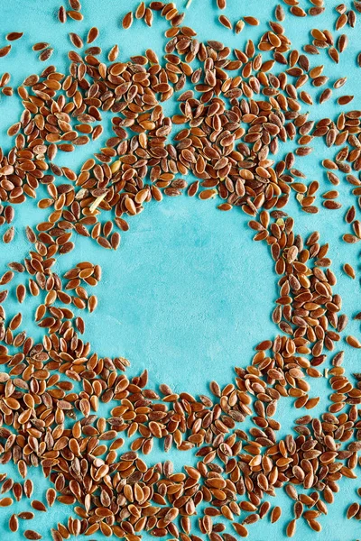 Вид зверху на невелику купу насіння льону круглої форми на синьому фоні — стокове фото