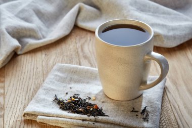 Rustik ahşap arka plan, seçici odak bir peçeteye dağınık çay yapraklar ile fincan seramik