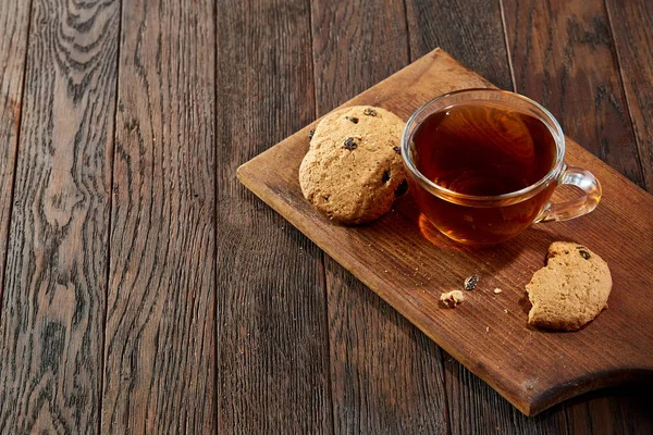 Taza de té con galletas en una tabla de cortar sobre un fondo de madera, vista superior — Foto de Stock