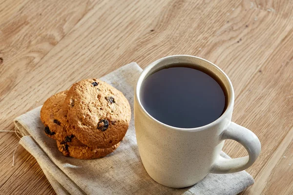 Chávena de porcelana com biscoitos de chocolate em guardanapo de algodão em um fundo de madeira rústica, vista superior — Fotografia de Stock