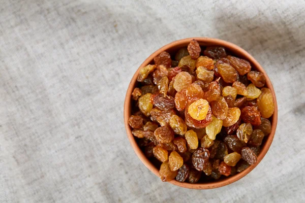 Ceramic bowl with golden raisins on light tablecloth, close-up, selective focus — Stock Photo, Image