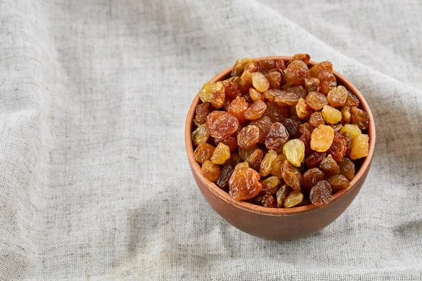 Ceramic bowl with golden raisins on light tablecloth, close-up, selective focus — Stock Photo, Image