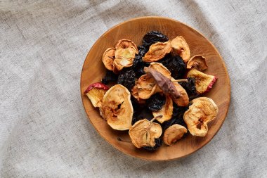 Yakın çekim ahşap kase kuru meyveler üzerinde hafif bir masa örtüsü ile