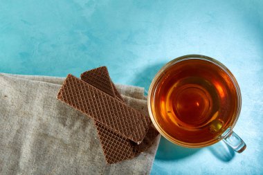 Cam bardak çay ve yulaf ezmesi çikolata kurabiye yakın çekim mavi zemin üzerine.