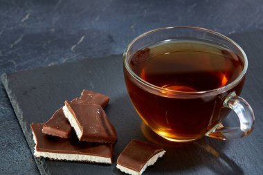 Cam bardak koyu grimsi mermer zemin üzerine çikolata parçaları ile siyah çay. Üstten Görünüm