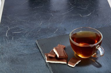 Cam bardak koyu grimsi mermer zemin üzerine çikolata parçaları ile siyah çay. Üstten Görünüm