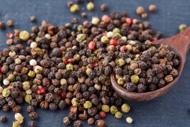 En koyu arka plan üzerinde tahta kaşık karabiber bileşimi görünüm yakın çekim.