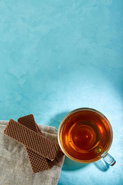 Glass cup of tea and oatmeal chocolate cookies close-up on blue background. — Stock Photo, Image