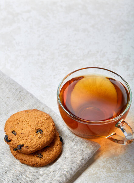 Top view closeup picture of tea in transparent cup with cookies and cotton napkin on white background, selective focus