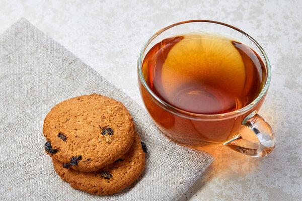 Top view closeup picture of tea in transparent cup with cookies and cotton napkin on white background, selective focus