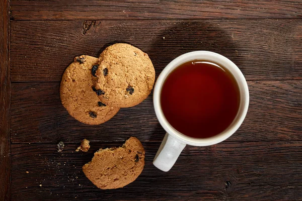 Taza de té con galletas, libro de trabajo y un lápiz sobre un fondo de madera, vista superior — Foto de Stock