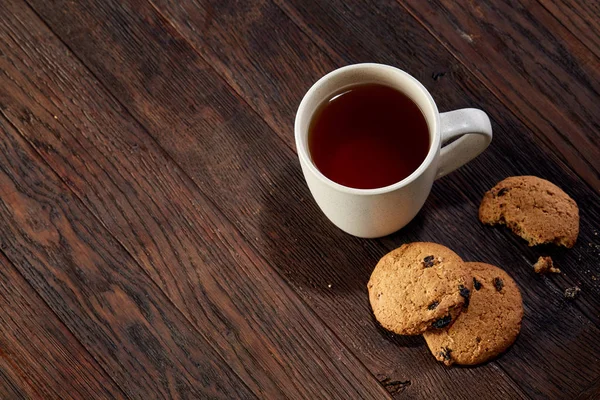 Cup of tea with cookies, workbook and a pencil on a wooden background, top view — Stock Photo, Image