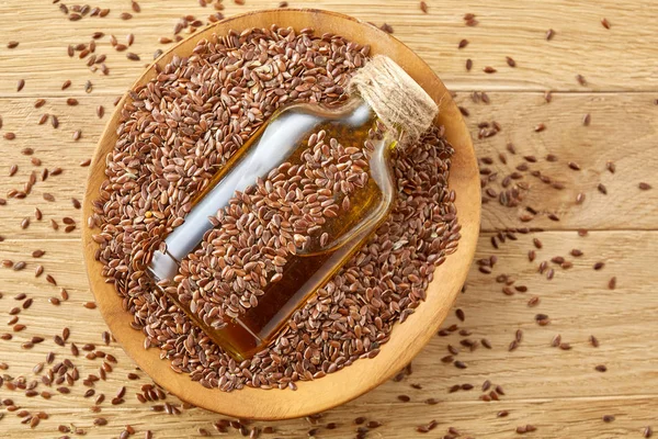 Vista superior imagen de primer plano semillas de lino y aceite de linaza en una botella de vidrio sobre un fondo de madera, poca profundidad de campo . — Foto de Stock