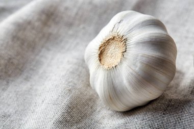 Düzenlenmiş bir pamuk masa örtüsü, sığ derinliği alan, seçici odak, makro sarımsak ampul görünümünü kapat