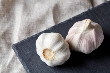 Düzenlenmiş siyah bir tahta parçası, alan, seçici odak, makro sığ derinliği iki sarımsak ampuller görünümünü kapat