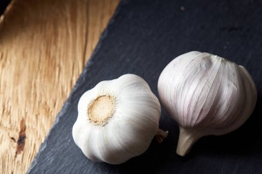 Düzenlenmiş siyah bir tahta parçası, alan, seçici odak, makro sığ derinliği iki sarımsak ampuller görünümünü kapat