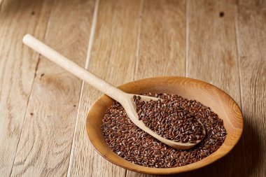 Tahta kaşıkla bir tabak rustik arka plan, üstten görünüm, yakın çekim, sığ derinlik-in tarla içinde keten tohumu