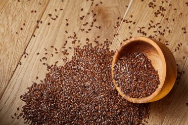 Linseeds bir rustik arka plan, yakın çekim, sığ alan, seçici odak derinliği ile devrilmiş bir ahşap kase