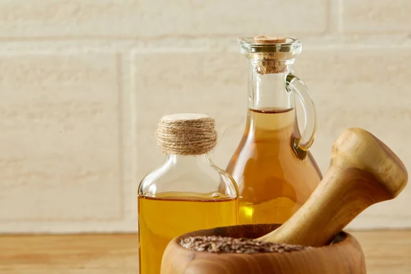 Bella composizione di vasi di olio di vetro, malta di legno e pestello con semi di lino, profondità di campo poco profonda — Foto Stock