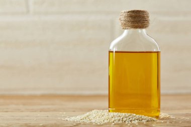 Soyulmuş susam yağı ahşap arka plan, yakın çekim, sığ derinlik-in tarla, seçici odak küçük bir şişe içinde