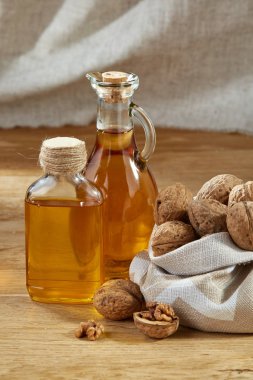 Aromatik yağ bir cam kavanoz ve şişe ahşap masa, torba ceviz ile yakın çekim.