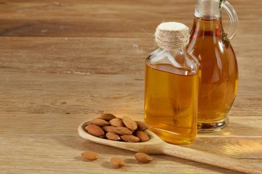 Aromatik yağ bir cam kavanoz ve şişe badem ahşap masa, bir kepçe ile yakın çekim.