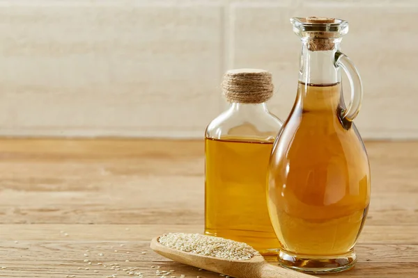 Keuken stilleven van glas olie potten en scoop met sesam op houten tafel, ondiepe scherptediepte, selectieve aandacht — Stockfoto