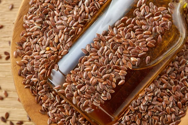 Vista superior imagen de primer plano semillas de lino y aceite de linaza en una botella de vidrio sobre un fondo de madera, poca profundidad de campo . — Foto de Stock
