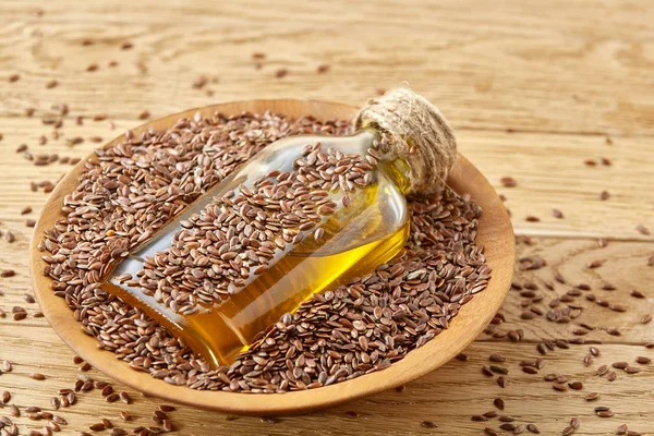 Top view closeup picture flax seeds and linseed oil in a glass bottle on a wooden background, shallow depth of field. — Stock Photo, Image