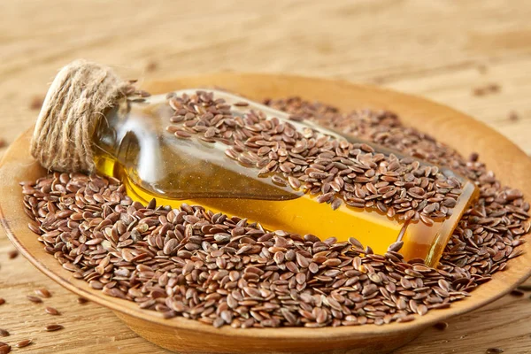 Top view closeup picture flax seeds and linseed oil in a glass bottle on a wooden background, shallow depth of field. — Stock Photo, Image