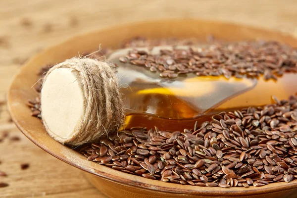 Top view closeup picture flax seeds and linseed oil in a glass bottle on a wooden background, shallow depth of field. — Stock Photo, Image