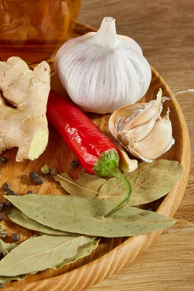 Conceptual composition of different spices and oil bottle on a wooden tray on rustic table, closeup, selective focus.