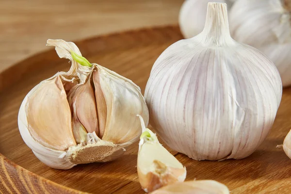 Knoflook close-up op houten plaat op rustieke achtergrond, ondiepe diepte van veld, selectieve aandacht, macro — Stockfoto