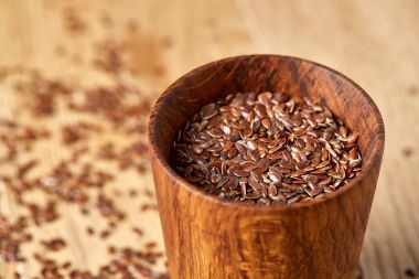 Linseeds bir rustik arka plan, yakın çekim, sığ alan, seçici odak derinliği ile devrilmiş bir ahşap kase