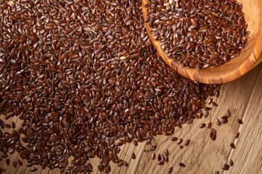 Linseeds bir rustik arka plan, yakın çekim, sığ alan, seçici odak derinliği ile devrilmiş bir ahşap kase