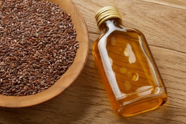 Ahşap arka plan, üstten görünüm, yakın çekim, seçici odak cam şişede kase ve keten tohumu yağı keten tohumu