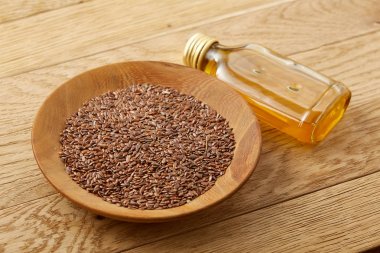 Ahşap arka plan, üstten görünüm, yakın çekim, seçici odak cam şişede kase ve keten tohumu yağı keten tohumu