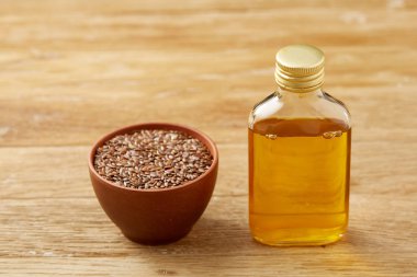 Ahşap arka plan, üstten görünüm, yakın çekim, seçici odak cam şişede kase ve keten tohumu yağı keten tohumu