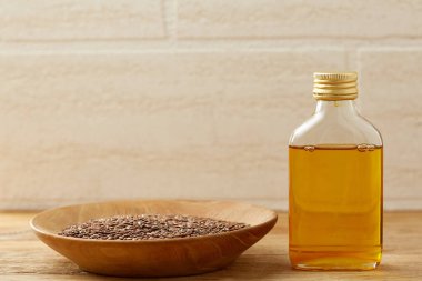 Ahşap arka plan, üstten görünüm, yakın çekim, seçici odak cam şişede kase ve keten tohumu yağı keten tohumu